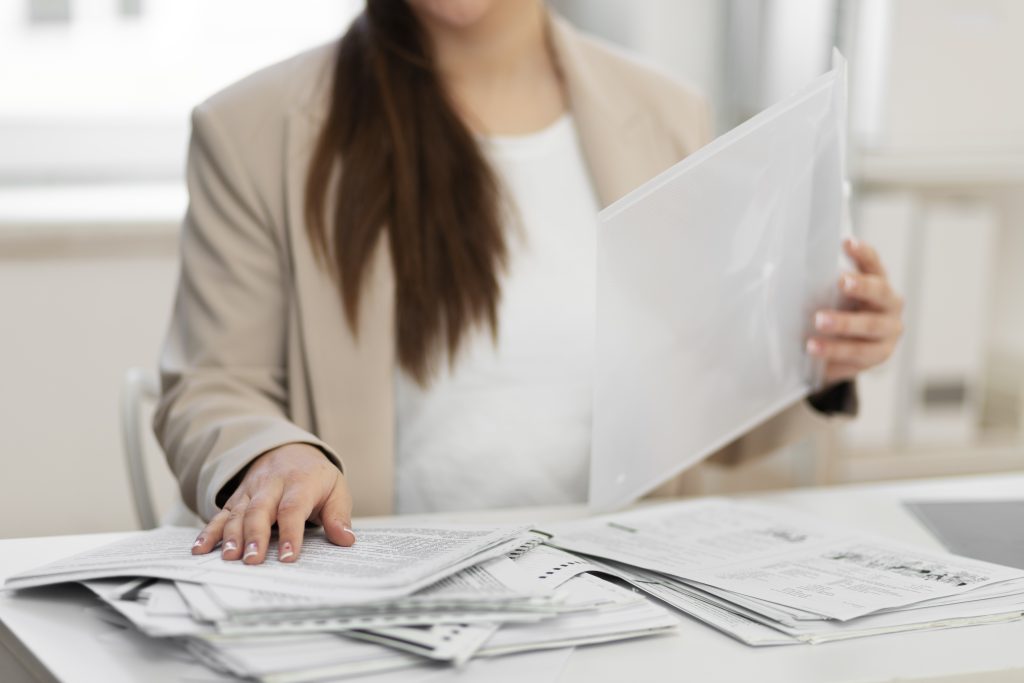 Kobieta porządkująca dokumenty i teczki na biurku w biurze firmy